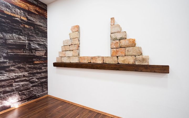 Ismaning: alte Ziegel auf einem Holzbrett an der weißen Wand.